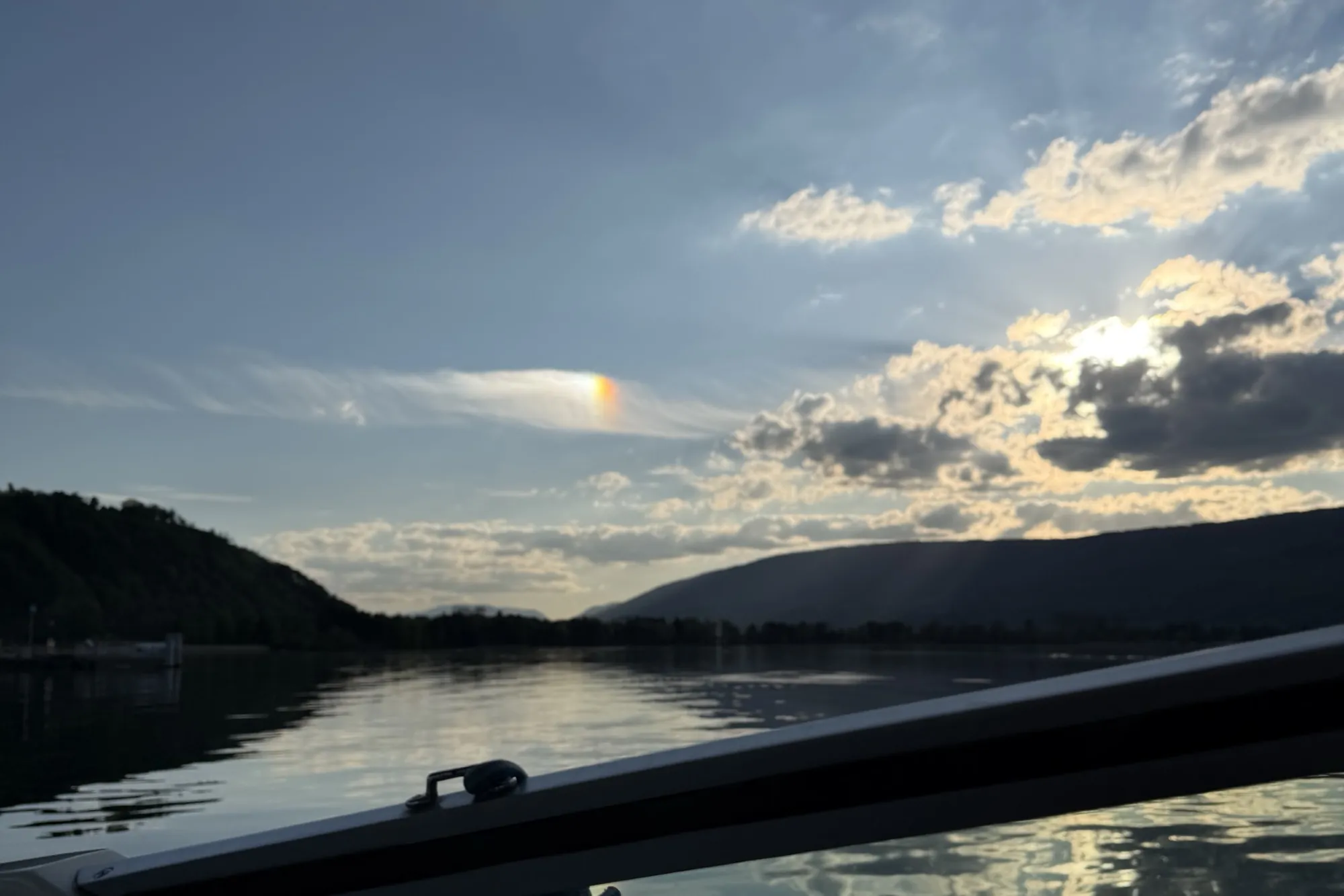 The view from on board across the lake to a wooded ridge in the evening light.